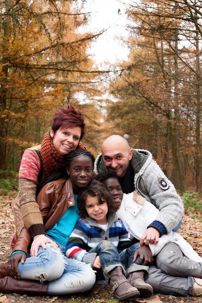 Portrait of a happy, mixed-race family posing in the woods in Autumn.