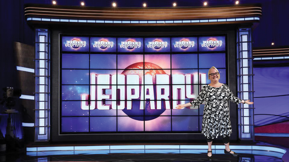 Erica Baltezore, EA Jeopardy! Champion standing proudly in front of the Jeopardy! board