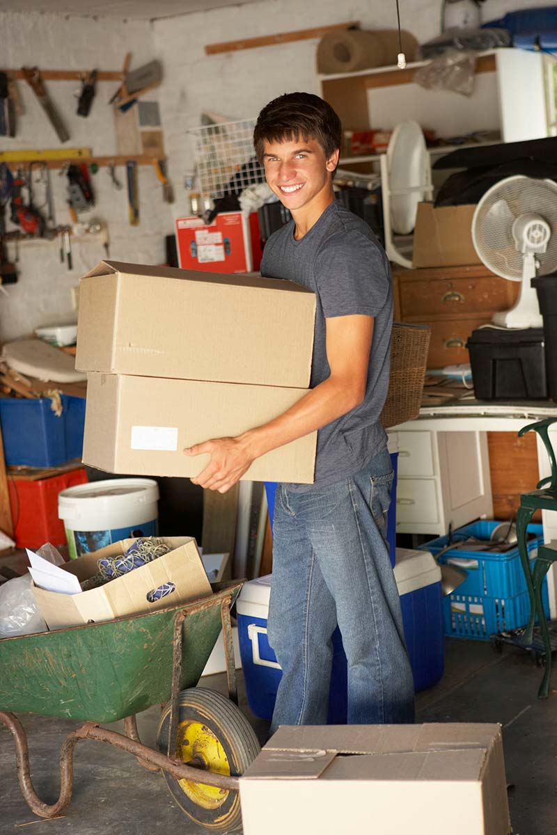 Young man packing boxes in preparation for a move into transitional housing. 